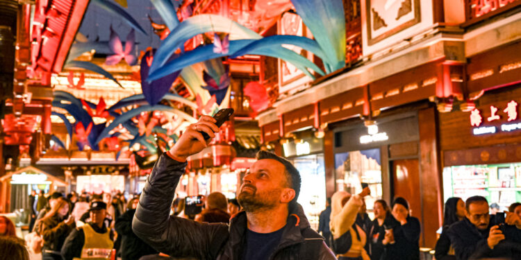 A traveler from Poland takes photos at the Yuyuan shopping center in Shanghai on Dec 4. China's visa-free policies, along with optimized payment options and other visitor-friendly services, have made traveling to the country more convenient, attracting an increasing number of foreign travelers. CHEN HAOMING/XINHUA