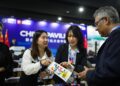 Staff members introduce a pamphlet to a guest during a side meeting marking the opening of the China Pavilion at the 29th Session of the Conference of the Parties to the UN Framework Convention on Climate Change, or COP29, in Baku, Azerbaijan, on November 11, 2024 (XINHUA)