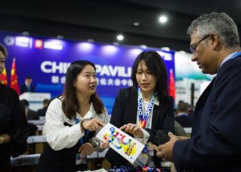Staff members introduce a  pamphlet to a guest during a side meeting marking the opening of the China Pavilion at the 29th Session of the Conference of the Parties to the UN Framework Convention on Climate Change, or COP29, in Baku, Azerbaijan, on November 11, 2024 (XINHUA)
