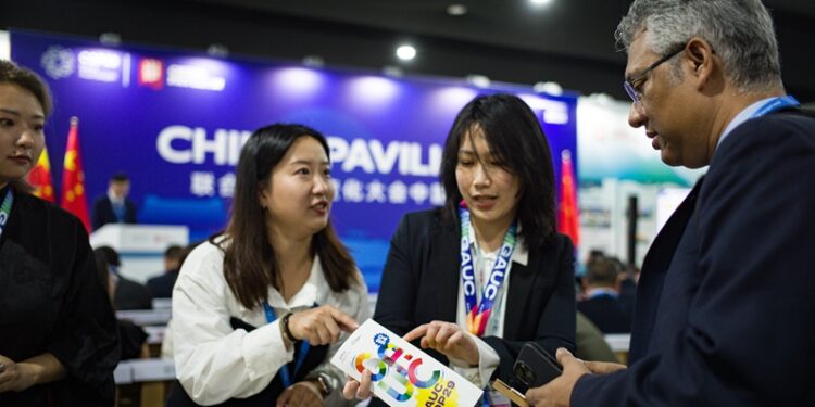 Staff members introduce a  pamphlet to a guest during a side meeting marking the opening of the China Pavilion at the 29th Session of the Conference of the Parties to the UN Framework Convention on Climate Change, or COP29, in Baku, Azerbaijan, on November 11, 2024 (XINHUA)