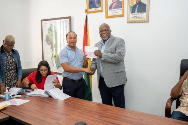 A public sector worker getting his $100,000 cash grant from Prime Minister Brigadier (Ret'd) Mark Phillips on December 24, 2024