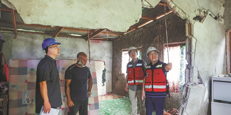 Experts from the China Earthquake Administration check a house on Wednesday that was damaged in a recent earthquake in Port Vila, Vanuatu. The administration sent four engineering experts to assist with post-earthquake response. The quake occurred on Dec 17, killing at least 14 people. LONG LEI/XINHUA