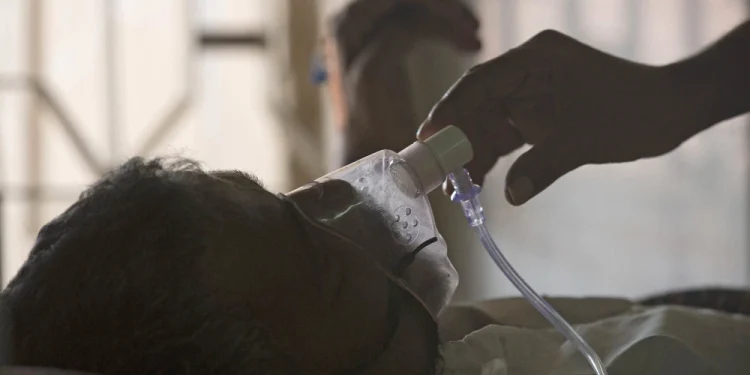 A relative adjusts a tuberculosis patient's oxygen mask in Hyderabad, India, in 2018.Mahesh Kumar A. / AP