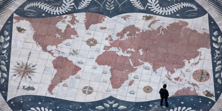 A man looks at a map of the world in Lisbon, Portugal [File: Armando Franca/AP]