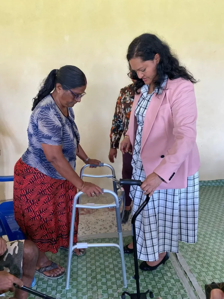 Minister of Human Service and Social Security, Dr Vindhya Persaud, hands over a walker to Hemwattie Ramlall