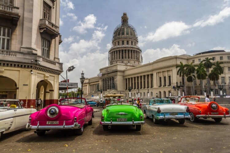 Classic cars that serve as tourist taxis line up in front of the National Capitol Building, or El Capitolio, in downtown Havana. Photo by Frank Carlson (PBS)