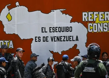 Police and national guard officers next to a mural reading, “Essequibo belongs to Venezuela” during a protest in Caracas this month.Credit...Juan Barreto/Agence France-Presse — Getty Images