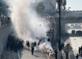 Police officers are enveloped in a cloud of smoke from tear gas and percussion grenades while guarding a highway onramp during a protest against federal immigration sweeps in downtown Los Angeles, California, June 8. REUTERS/Omar Younis