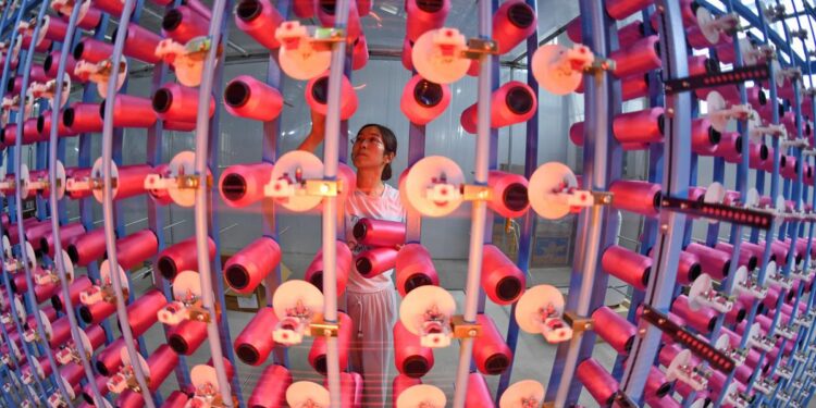 A worker handles products at the Shu Brocade Workshop of the Chengdu Shu Brocade Research Institute, a private enterprise in Chengdu, Sichuan province, on July 3. LI XIANGYU / FOR CHINA DAILY