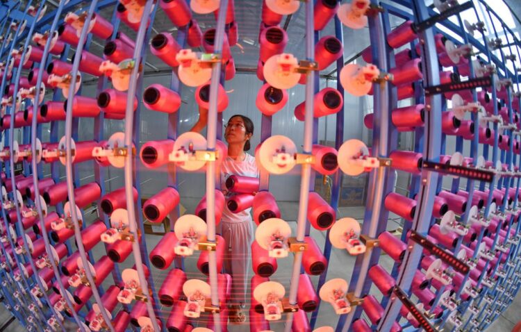 A worker handles products at the Shu Brocade Workshop of the Chengdu Shu Brocade Research Institute, a private enterprise in Chengdu, Sichuan province, on July 3. LI XIANGYU / FOR CHINA DAILY