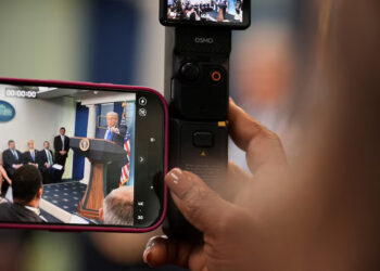 A member of the media records U.S. President Donald Trump speaking during a press conference, after the U.S. Supreme Court dealt a blow to the power of federal judges by restricting their ability to grant broad legal relief in cases as the justices acted in a legal fight over President Donald Trump's bid to limit birthright citizenship, in the Press Briefing Room at the White House in Washington D.C., June 27, 2025. REUTERS/Ken Cedeno/File Photo