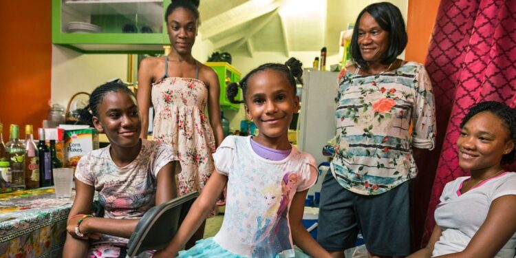 © UNICEF/Roger LeMoyne A young girl shows off her dress in front of her family at home on the island of Antigua, in the Caribbean.