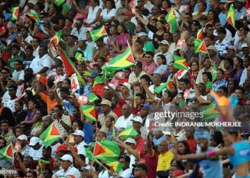 Spectators wave the Guyanese flag as West Indies cricketer Shivnarine Chanderpaul plays a shot against Ireland during their ICC World Twenty20 2010 match at the Providence Stadium in Guyana on April 30, 2010. West Indies won the toss and electing to bat are 37 for 1 wicket after 5 overs. The ICC World Twenty20 2010 takes place in the West Indies from 30 April to 16 May. AFP PHOTO/Indranil MUKHERJEE (Photo credit should read INDRANIL MUKHERJEE/AFP via Getty Images)