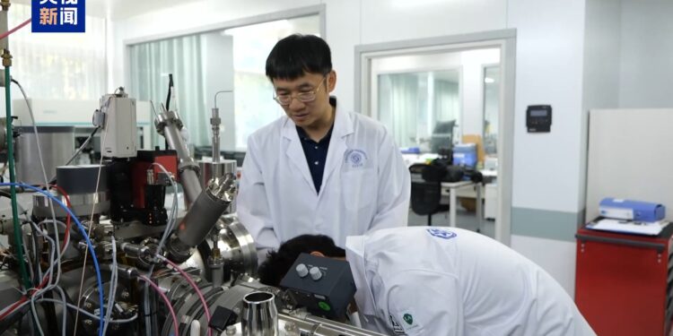 Yang Wei (L), a researcher at the Institute of Geology and Geophysics under the Chinese Academy of Sciences, studies lunar samples with his colleague in Beijing, China. /CMG