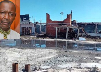 General Secretary of the Guyana Trades Union Congress Lincoln Lewis and the burnt out remains of the GTUC headquarters.
