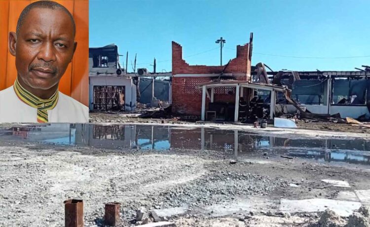 General Secretary of the Guyana Trades Union Congress Lincoln Lewis and the burnt out remains of the GTUC headquarters.