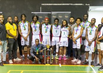 Members of the University of Guyana Trojans celebrate with their coaches; Sports Organiser, Osafa Dos Santos; and supporters following their big win at the Cliff Anderson Sports Hall