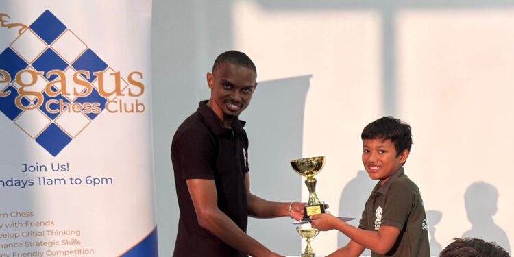 Julian Mohabir receiving his first-place trophy from FM Anthony Dayton.