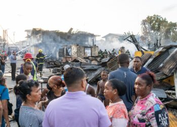 Azruddin Mohamed (in purple polo shirt) talking with the Albouystown fire victims