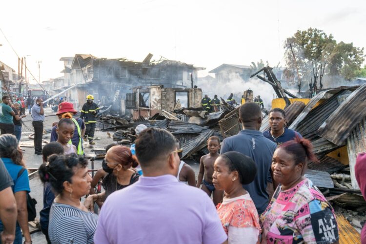 Azruddin Mohamed (in purple polo shirt) talking with the Albouystown fire victims