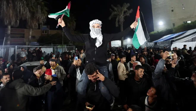 A man waves Palestinian flags as Palestinians react to news on a ceasefire deal with Israel, in Deir Al-Balah in the central Gaza Strip, January 15, 2025.