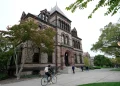 Passers-by walk and ride along a path on the campus of Brown University, in Providence, R.I., Monday, Oct. 12, 2020. (AP Photo/Steven Senne, File)