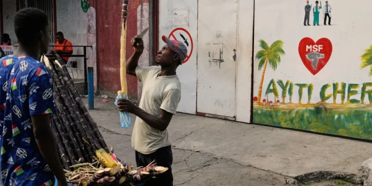 A vendor sells sugarcane next to the entrance of the Doctors Without Borders (MSF) clinic in Port-au-Prince, Haiti, Wednesday, Oct. 15, 2025, after the organization announced the facility’s closure due to ongoing violence. (AP Photo/Odelyn Joseph)