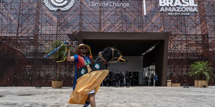 A performer wearing traditional attire poses for a photo in front of the COP30 venue in Belem, Brazil, Nov. 6, 2025. (Xinhua/Wang Tiancong)