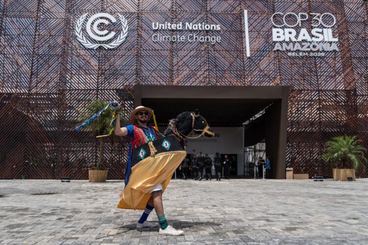 A performer wearing traditional attire poses for a photo in front of the COP30 venue in Belem, Brazil, Nov. 6, 2025. (Xinhua/Wang Tiancong)