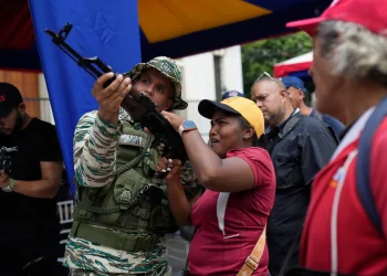 A member of the Bolivarian National Militia shows a woman how to operate a weapon during military exercises in Caracas, Venezuela, Saturday, Sept. 20, 2025. | AP Photo/Ariana Cubillos