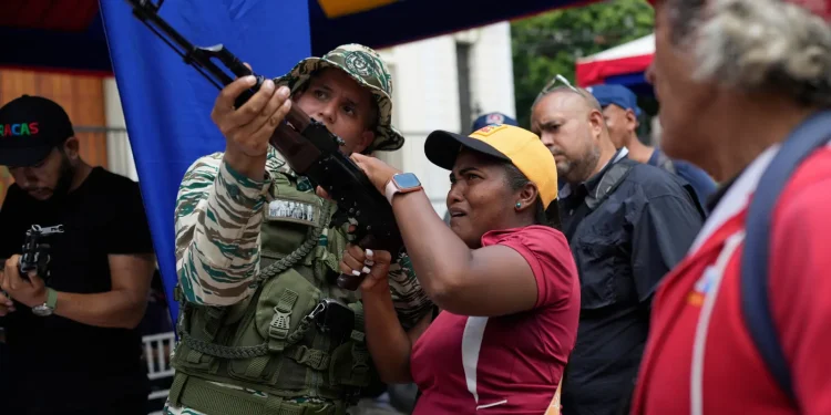 A member of the Bolivarian National Militia shows a woman how to operate a weapon during military exercises in Caracas, Venezuela, Saturday, Sept. 20, 2025. | AP Photo/Ariana Cubillos