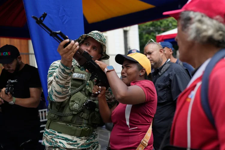 A member of the Bolivarian National Militia shows a woman how to operate a weapon during military exercises in Caracas, Venezuela, Saturday, Sept. 20, 2025. | AP Photo/Ariana Cubillos