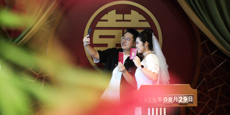 A couple poses for photos at a marriage registration office in Gusu district, Suzhou, East China's Jiangsu province, Aug 29. [Photo/Xinhua]
