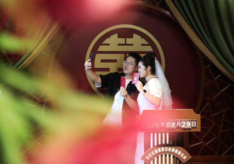 A couple poses for photos at a marriage registration office in Gusu district, Suzhou, East China's Jiangsu province, Aug 29. [Photo/Xinhua]