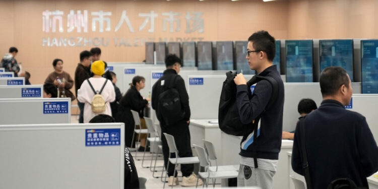 Jobseekers gather information at an employer's stand during a job fair held in Hangzhou, Zhejiang province, on Nov 12. [Photo/Xinhua]
