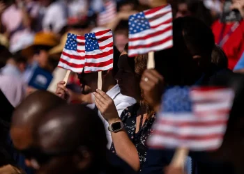 New US citizens use handheld fans to take shade from the sun during a naturalization ceremony at George Washington's Mount Vernon in Mount Vernon, Virginia, US, on Friday, July 4, 2025. Kent Nishimura/Bloomberg via Getty ImagesKent Nishimura—Bloomberg via Getty Images