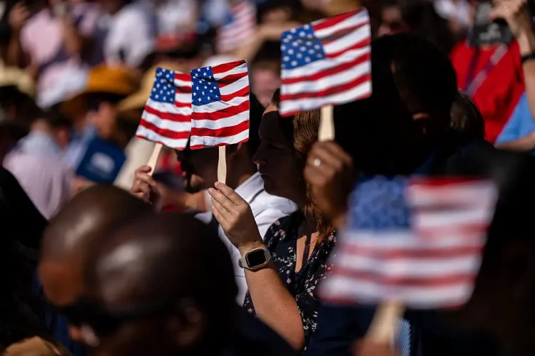 New US citizens use handheld fans to take shade from the sun during a naturalization ceremony at George Washington's Mount Vernon in Mount Vernon, Virginia, US, on Friday, July 4, 2025. Kent Nishimura/Bloomberg via Getty ImagesKent Nishimura—Bloomberg via Getty Images