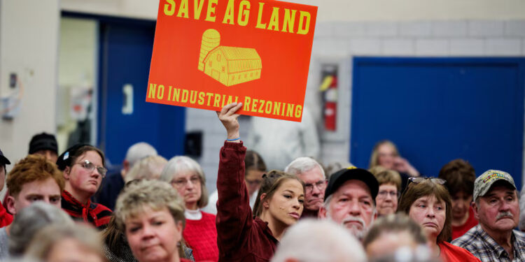 A community member holds a sign against a plan of Talen Energy to rezone land from agricultural to industrial to build a data center, at the Montour County Planning Commission meeting in Danville, Pennsylvania, U.S. November 19, 2025. REUTERS/Hannah Beier Purchase Licensing Rights