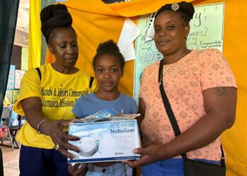 Morvia Reid Williams (L) handing out a nebulizer at medical mission in Little London, Westmoreland.
