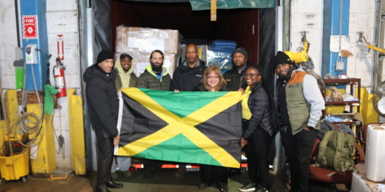 Jamaica’s Ambassador to the United States, His Excellency Major General (Ret’d) Antony Anderson (right), President and CEO of EMD Sales, Ms. Elda Devaré (centre), and Ms. Natasha Forrest proudly display the Jamaican flag in front of the 40-foot container packed with essential supplies bound for Jamaica. Looking on are members of staff from the Embassy of Jamaica and EMD Sales at the company’s warehouse in Baltimore, Maryland. Photo Derrick Scott.