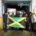 Jamaica’s Ambassador to the United States, His Excellency Major General (Ret’d) Antony Anderson (right), President and CEO of EMD Sales, Ms. Elda Devaré (centre), and Ms. Natasha Forrest proudly display the Jamaican flag in front of the 40-foot container packed with essential supplies bound for Jamaica. Looking on are members of staff from the Embassy of Jamaica and EMD Sales at the company’s warehouse in Baltimore, Maryland. Photo Derrick Scott.