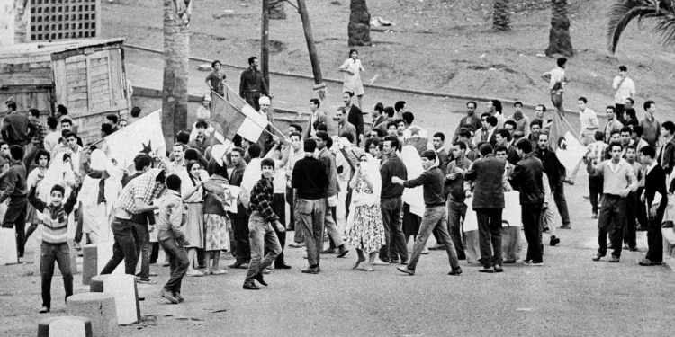 Young Muslims gather around the green and white FLN rebel flag in Diar el Mahcoul, a suburb of Algiers, ignoring French orders to stay at home, Oct. 31, 1969. (AP Photo/ H. Babout, file)