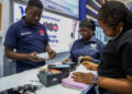 Staff members assist customers at a shop selling electronic products at the East Africa Commercial and Logistics Center (EACLC) in Dar es Salaam, Tanzania, Dec. 19, 2025. (Xinhua/Emmanuel Herman)