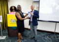 His Excellency Professor Compton Bourne, OE, presents a copy of his book to Dr Simone Bernard, Acting University Librarian