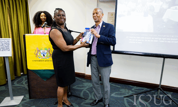 His Excellency Professor Compton Bourne, OE, presents a copy of his book to Dr Simone Bernard, Acting University Librarian