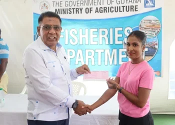 Minister Zulfikar Mustapha handing over a cheque to a female fisherfolk during the distribution at the Everest Cricket Club