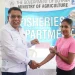 Minister Zulfikar Mustapha handing over a cheque to a female fisherfolk during the distribution at the Everest Cricket Club
