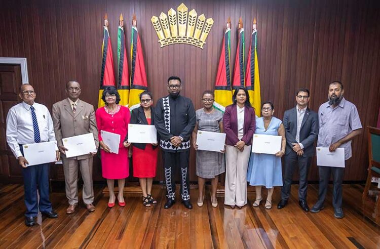 President Dr irfaan Ali (at centre), along with the seven members of the Teaching Service Commission (holding their instruments of appointment) and Minister of Education, Sonia Parag (fourth from right) and Minister of Public Service, Government Efficiency and Implementation (second from right) (Delano Williams photo- Guyana Chronicle)