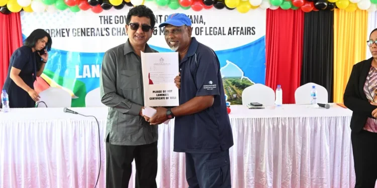 Minister Anil Nandlall (l) handing over Certificate of Title to a Cotton Tree resident (DPI photo)