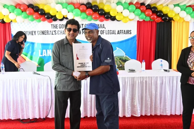 Minister Anil Nandlall (l) handing over Certificate of Title to a Cotton Tree resident (DPI photo)
